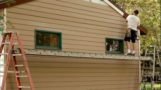 Crew installing new lap siding on the side of a two-story house